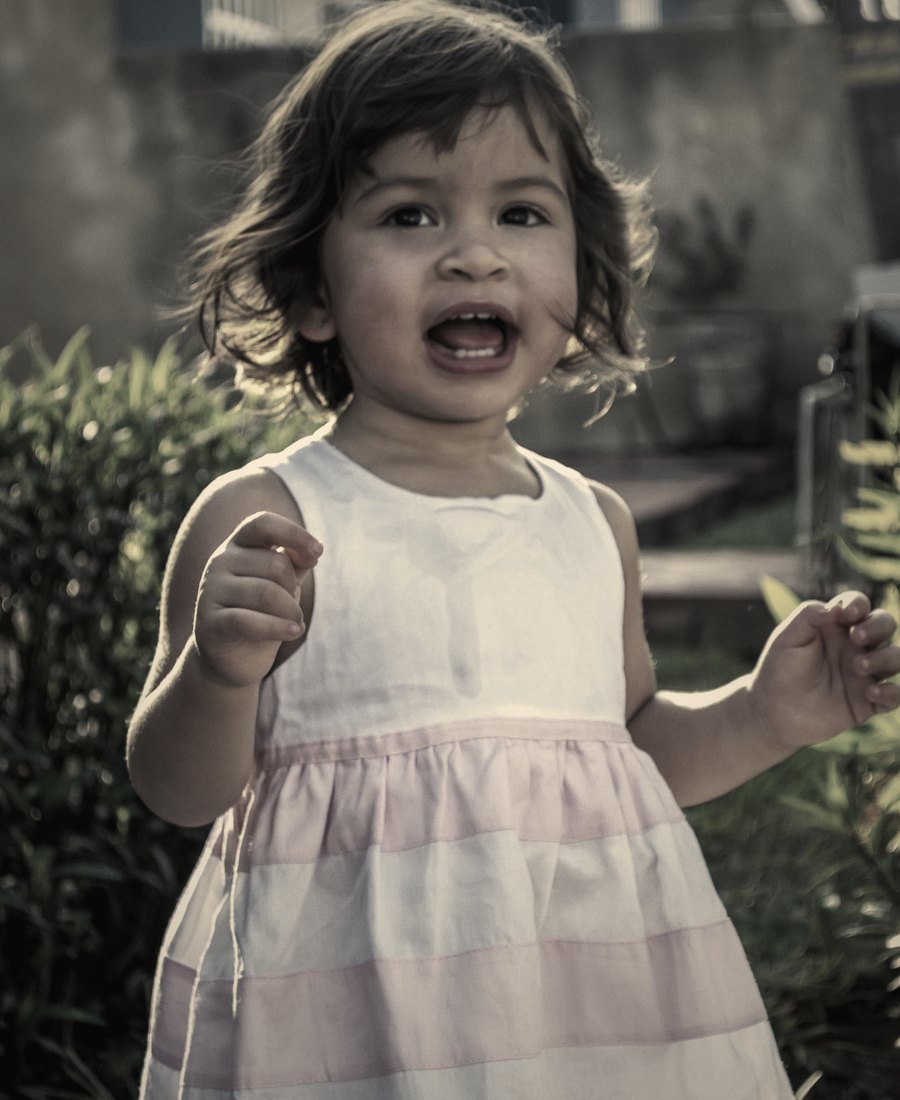 A little girl laughing in a sunlit garden