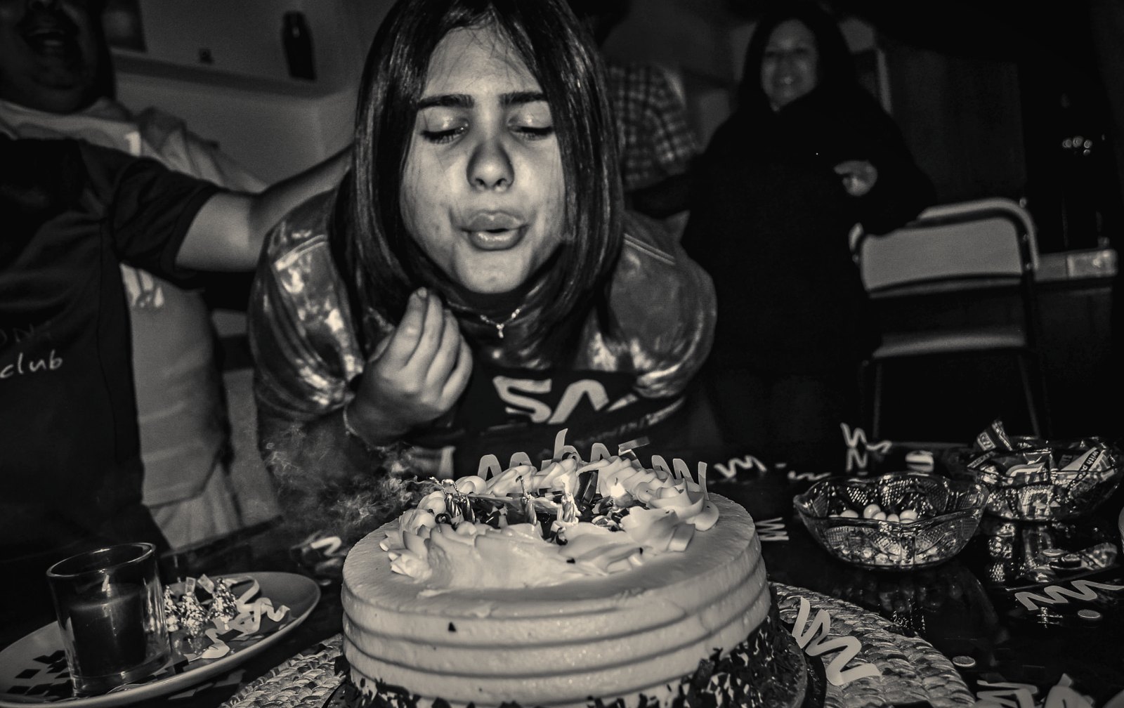 A girl blowing out her birthday candles, captured in black and white